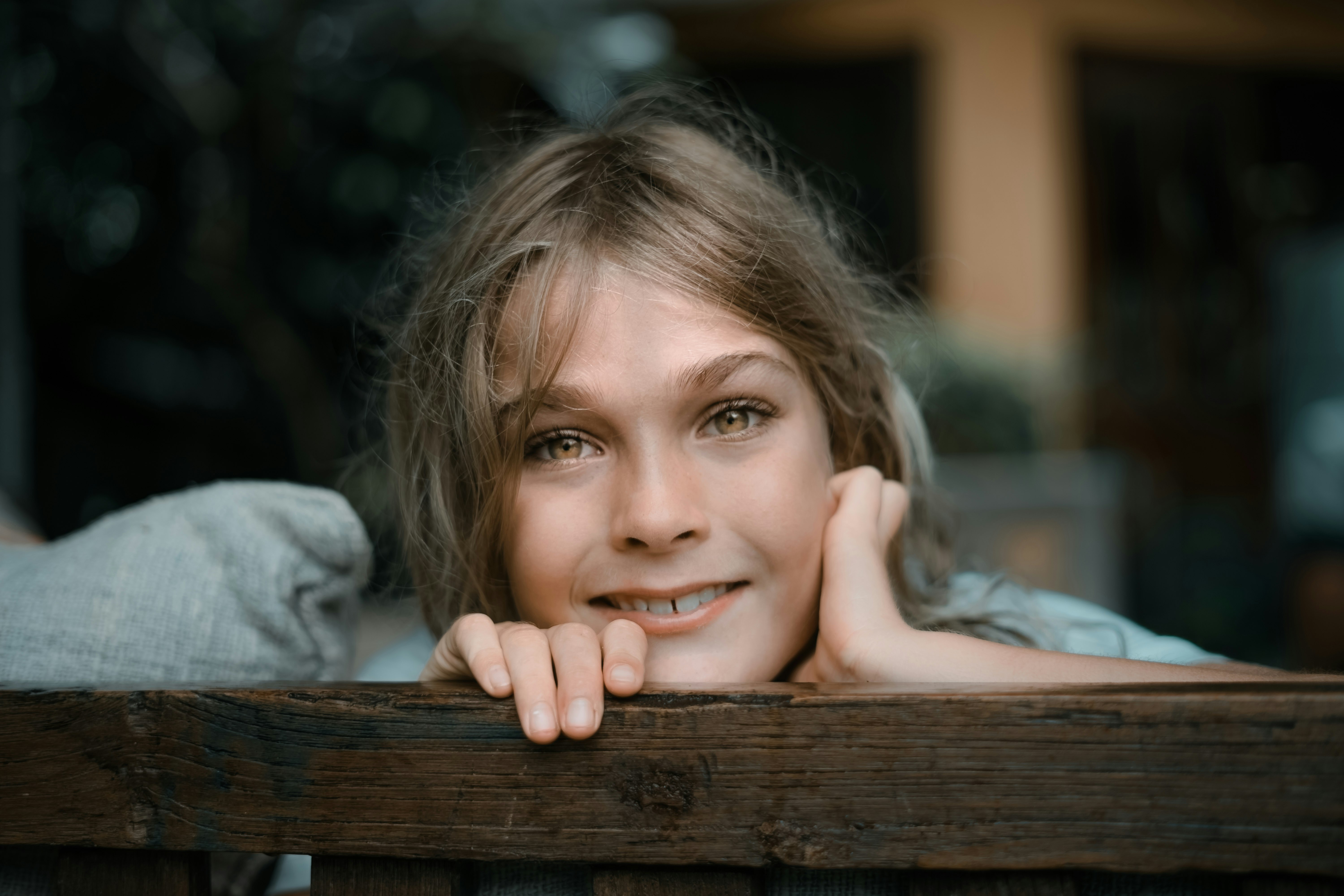 girl in gray sweater lying on brown wooden bench